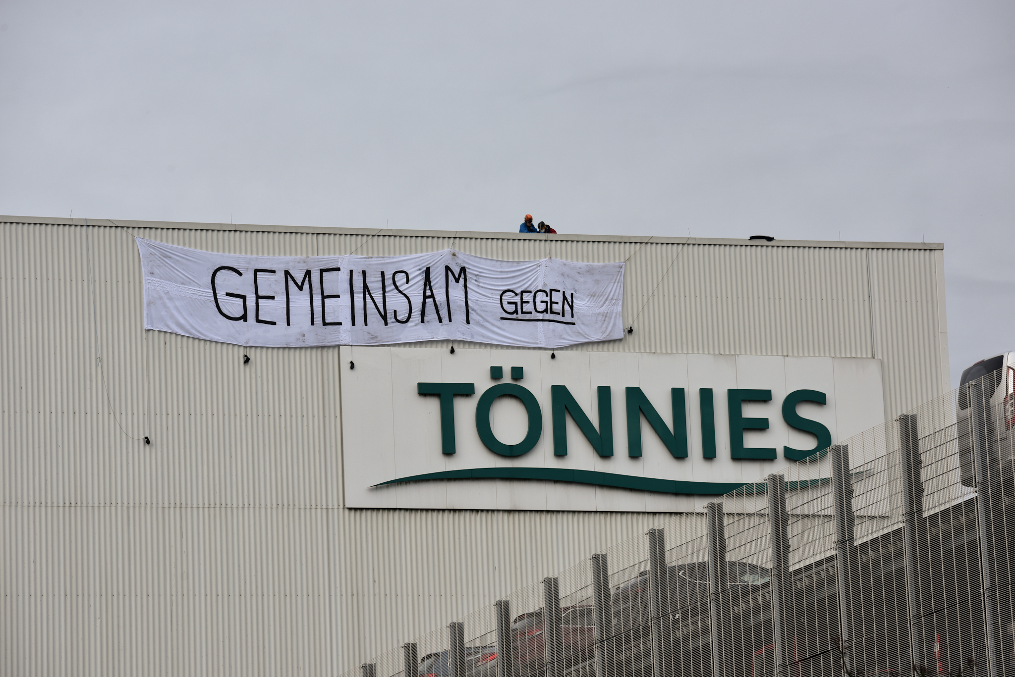 schlachthof von tönnies mit angebrachtem banner, es ergibt sich der schriftzug: gemeinsam gegen tönnies